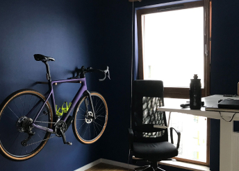 Bike hanging on a dark blue wall next to a chair and desk
